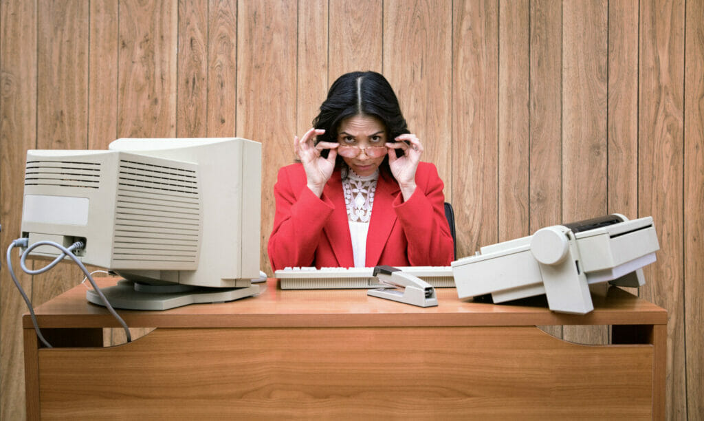 A woman on a telephone. Office looks like the 1980s